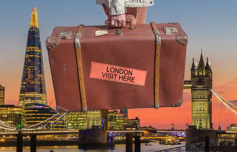 Vintage brown leather suitcase with travel label on background of the Shard and Tower Bridge..