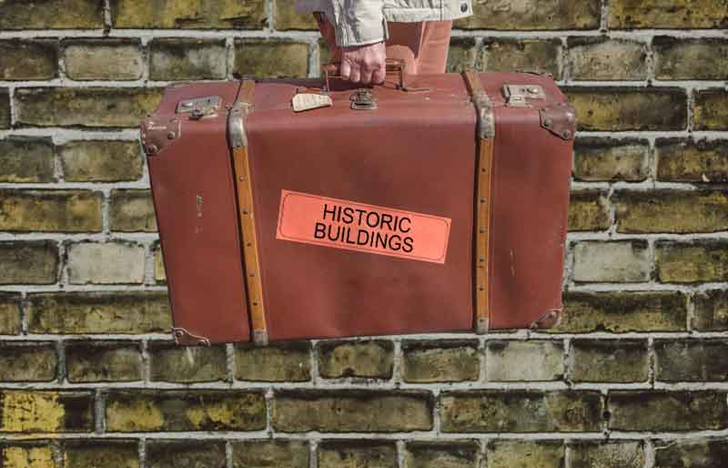 Vintage brown leather suitcase with category travel label on yellow brick background.