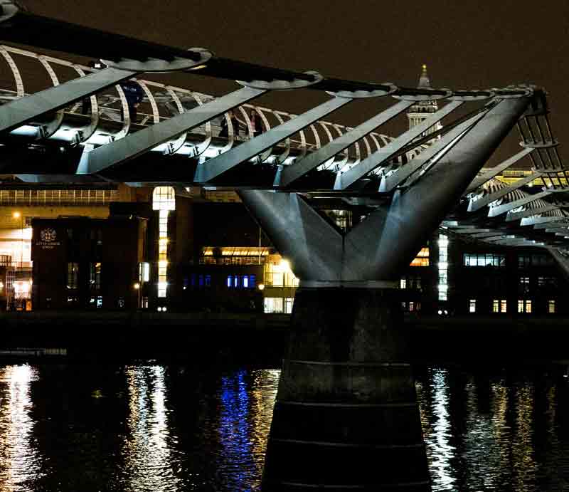 Millennium Bridge at night Illuminated and refected in the Thames.